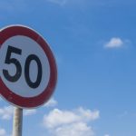 low angle view of road sign 50km/h against clear blue sky